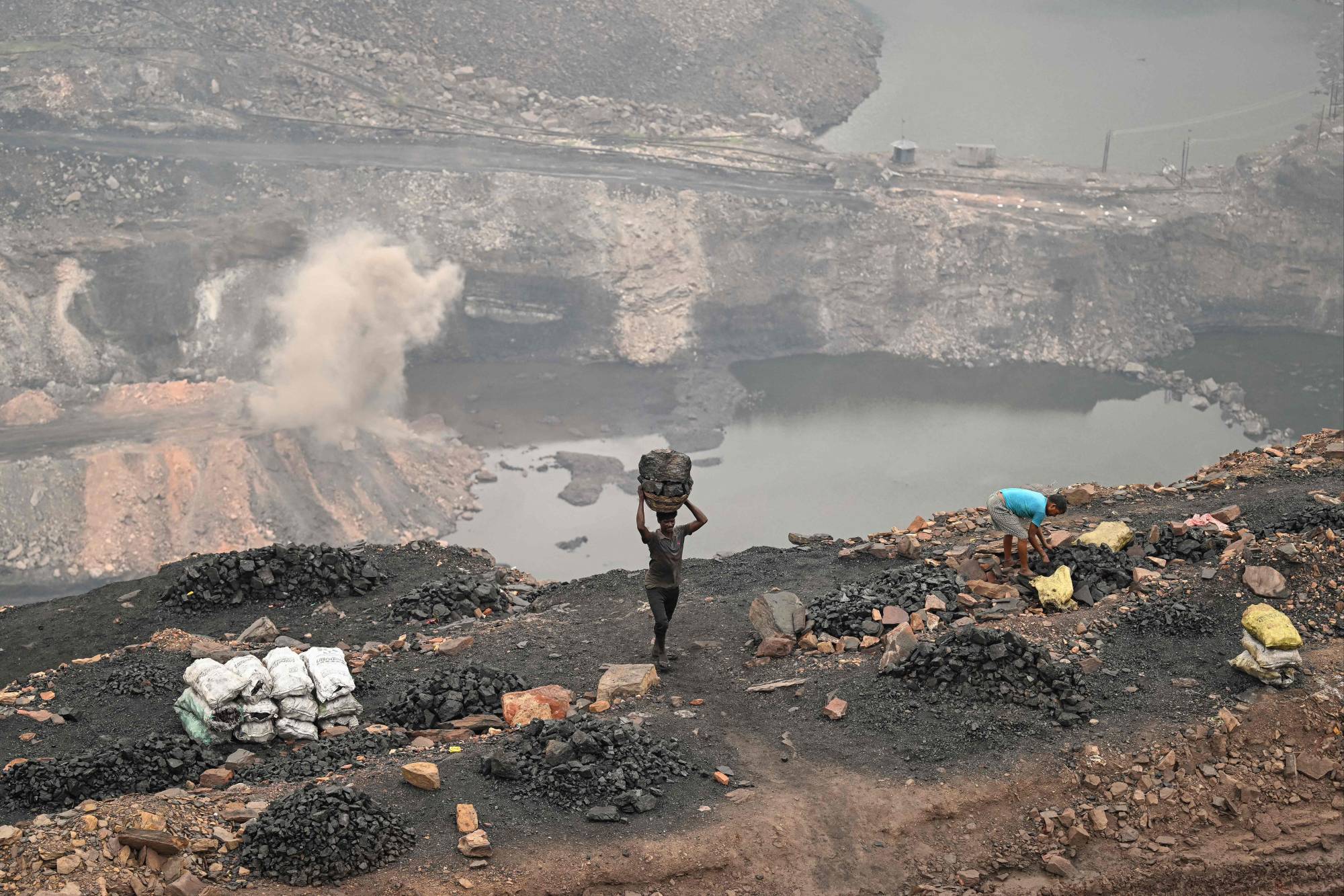 A coal picker carries coal at an open cast mining site on the outskirts of Dhanbad, India, earlier this month.  | AFP-JIJI