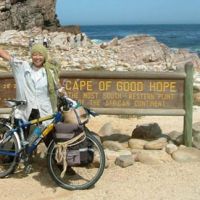 Endings, new beginnings: Mio Yamasaki waves in triumph in 2005 at the endpoint of her bicycle tour &#8212; the Cape of Good Hope. | COURTESY OF MIO YAMASAKI