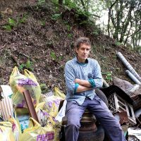 Poet Stephen Gill sits amid refuse collected from Mount Ogura in western Kyoto suburb during a cleanup operation in early October. | JANE SINGER PHOTOS