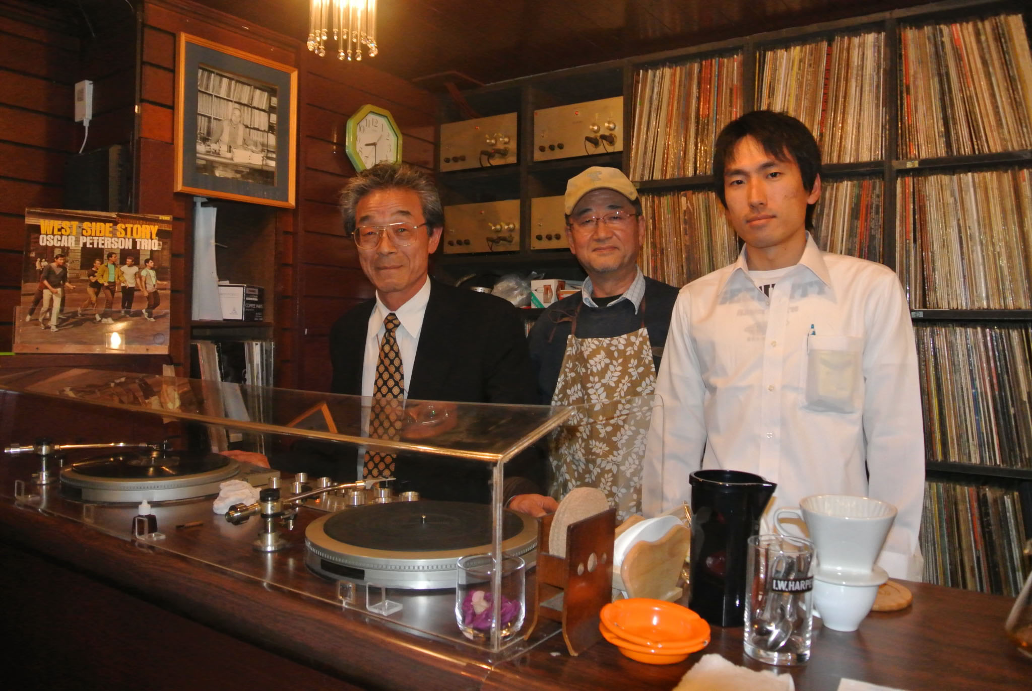 The beat goes on: Masataka Yusa (left), who heads the Chigusa Kai supporters group, with two staff members and some of the cafe's more than 3,000 records. | ERIKO ARITA PHOTOS