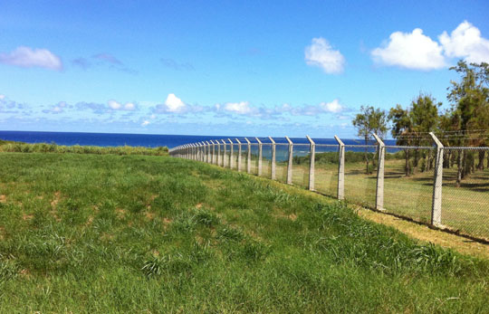 Keep out: A fence topped with razor-wire separates the U.S. Iejima Island Auxiliary Airfield (right) from Japan. | JON MITCHELL