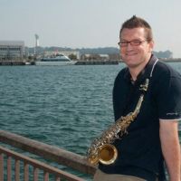 Before: Briton John Loynes, a resident of Iwaki, Fukushima Prefecture, poses with his saxophone at a concert held at Iwaki Port in a photo taken before the March 11, 2011, tsunami ravaged the city\'s coastline. | PHOTOS COURTESY OF JOHN LOYNES