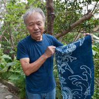 Dyed-in-the-hemp: Masanao Shiroma holds up a finished piece of aizome &#8212; Ryukyu-ai indigo dyed hemp &#8212; in the grounds of Aikaze, near the Motobu region in Okinawa. | STEPHEN MANSFIELD PHOTOS