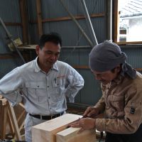 Pagoda prep (Top to bottom): Toshio Fujino, head contractor at Seirinji Temple, oversees the carving of a dait&#333; load-bearing block; Fujino adjusts a model of Seirinji\'s pagoda-in-progress beside chisels and a long-handled yari kana (hewing knife); and Fujino, from the Nishizawa Koumuten engineering firm, explains the function of the pagoda\'s shinbashira (heart pillar). | KIT NAGAMURA PHOTOS