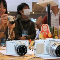 Viewfinder: A visitor tries out an Olympus Corp.\'s Pen mirrorless digital camera featuring interchangeable lenses at CP+2012, the country\'s largest camera show, which kicked off Thursday at Pacifico in Yokohama. | SATOKO KAWASAKI