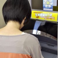 Handy: A customer touches a palm-scanning ID sensor at Ogaki Kyoritsu Bank ATM in Hashima, Gifu Prefecture, on Wednesday. | KYODO