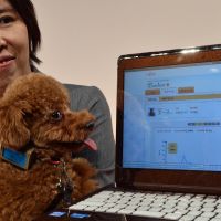 Canine computing: Yoko Mitsuyama of Fujitsu Ltd. holds her pet Ace wearing a device that monitors a dog\'s health. | AFP-JIJI