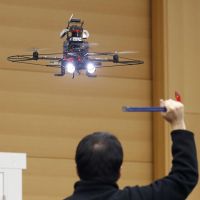 Big brother in Japan: A drone prototype is seen videotaping a man acting as an intruder near a building Wednesday. | KYODO