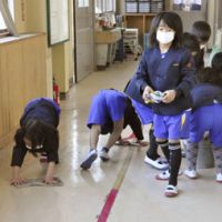 Extracurricular: Children clean a hallway covered with volcanic ash at their elementary school Monday in Takaharu, Miyazaki Prefecture. | KYODO PHOTO
