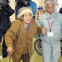 While the getting is good: An elderly woman is escorted to a shelter Thursday in Miyakonojo, Miyazaki Prefecture, after evacuating her home near Mount Shinmoe amid the threat of rain-triggered volcanic ash slides. | KYODO PHOTO