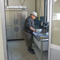 Coming back: Masakazu Haga stands at the sink in his temporary fish processing compound in Otsuchi, Iwate Prefecture, last month. | SETSUKO KAMIYA
