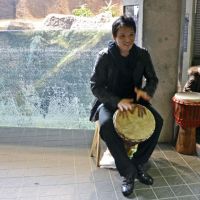 Gator aid: Percussionist Goshin Moro beats a drum by the alligator pen at Maruyama Zoo in Sapporo on Monday. | KYODO