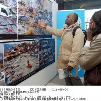 Glimpses of destruction: Visitors view photos of the March 11 disasters Monday at U.N. headquarters in New York. | KYODO