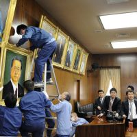 Larger than life: Democratic Party of Japan kingpin Ichiro Ozawa watches workers hang his portrait in a Lower House facility Monday. | KYODO
