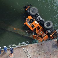Over the edge: Investigators look down on a mobile crane that fell into the Yodogawa River in Fukushima Ward, Osaka, on Wednesday. | KYODO