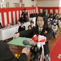 Onward and upward: A student from Tomioka No. 1 Elementary School who was displaced by the Fukushima nuclear crisis receives a graduation certificate Friday at a different school in Miharu, Fukushima Prefecture. | KYODO