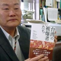 Witness: Nobuto Hirano, a representative of a Nagasaki-based liaison group for atomic bomb survivors overseas, holds a recently published book containing testimonies by Taiwanese survivors at Nagasaki City Hall. | KYODO