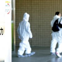Fukushima foothold: Workers in protective suits leave Tokyo Electric Power Co.\'s newly opened regional headquarters in Fukushima Prefecture on Friday at J Village in the town of Naraha. | KYODO