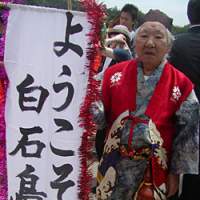 Man-chan, along with his friend Kio-chan, are there in a flash when visitors to Shiraishi arrive. The banner reads, \"Welcome to Shiraishi Island.\" | AMY CHAVEZ PHOTO