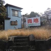 Unwanted: A corner lot for sale is overgrown with grass and weeds in Sakura, Chiba Prefecture. Building your home can come at quite a cost