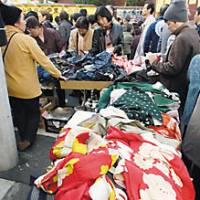 Shoppers examine old kimono and used clothes (above) at the Setagaya Boroichi flea market in Tokyo, which attracts around 800,000 people searching for antiques to craft goods to bric-a-brac. | YOSHIAKI MIURA PHOTOS