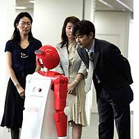 A Fujitsu Ltd. employee responds to an enon robot during a Tuesday demonstration in Tokyo as other employees look on. | PHOTO COURTESY OF DAIMLERCHRYSLER JAPAN CO.