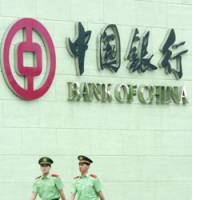 Security officials walk in front of the Bank of China\'s head office here Thursday, the day it went public on the Hong Kong Stock Exchange. | SATOKO KAWASAKI PHOTO