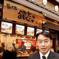 Morio Sase, founder and president of HotLand Corp., holds a serving of \"takoyaki\" octopus dumplings in front of his company\'s Ginza outlet in Tokyo in April. | YOSHIAKI MIURA PHOTO