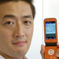Takuya Miyata, founder and chief executive officer of J-Magic Inc., displays his firm\'s kaocheki site on his cell phone at his company in Minato Ward, Tokyo. The service\'s analysis says Miyata looks like popular comedian Junji Takada. | YOSHIAKI MIURA PHOTO