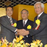 The leaders of the three major business organizations, (from left) Masamitsu Sakurai of the Japan Association of Corporate Executives (Keizai Doyukai), Fujio Mitarai of the Japan Business Federation (Nippon Keidanren) and Tadashi Okamura of the Japan Chamber of Commerce and Industry, clasp hands at a joint news conference in Tokyo on Monday. | YOSHIAKI MIURA PHOTO