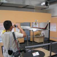 Plane view: A photographer takes a snap of a model of the Mitsubishi Regional Jet at the International Media Center in Rusutsu, Hokkaido, on Tuesday. | JUN HONGO