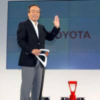 Winging it: Toyota Motor Corp. Executive Vice President Takeshi Uchiyamada demonstrates the Winglet personal transportation vehicle in Tokyo on Friday. | YOSHIAKI MIURA PHOTO