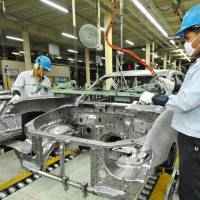 Back online: Workers assemble a car at a Mitsubishi Motors Corp. plant in Laem Chabang, Thailand, after the factory resumed production Monday. | KYODO