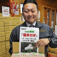 Rice alternative: An official in the village of Sakai, Nagano Prefecture, shows packages of Fukko \"soba\" on Monday. | KYODO PHOTO