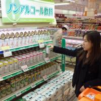 Less filling: A shopper with a young child picks up a nonalchoholic drink at an Ario store operated by the Ito-Yokado supermarket chain in Katsushika Ward, Tokyo, on Tuesday. | KYODO