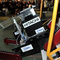 Stair master:  The  Tsubaki robot, developed by a startup firm of the Chiba Institute of  Technology and carrying a camera developed by Hitachi Ltd., climbs a set of stairs during a demonstration in Chiba Prefecture on Wednesday. | YOSHIAKI MIURA