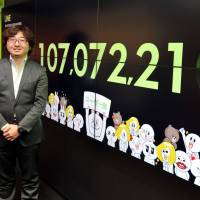 Line drive hit: NHN Japan Corp. CEO Akira Morikawa stands in his office in Tokyo on Feb. 5, with the number of Line users proudly on display. | YOSHIAKI MIURA