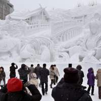 Frozen in time:  Visitors on Tuesday to the Sapporo Snow Festival view a gigantic sculpture based on an ancient Shinto myth at the start of the annual weeklong event. | KYODO