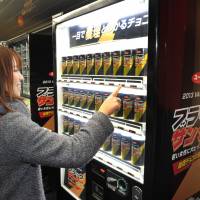 Love at first sight: A passenger gets a free can of Black Thunder chocolate bars Saturday from a vending machine set up for Valentine\'s Day at the Marunouchi Line\'s subway stop inside Shinjuku Station, Tokyo. | YOSHIAKI MIURA