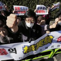 Nuclear reaction: South Korean residents of Japan hold a banner and raise their fists Wednesday during a Tokyo protest rally outside the General Association of Korean Residents to condemn North Korea\'s nuclear test the previous day. | AP