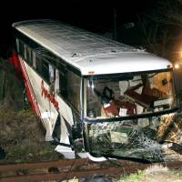 Train wreck: A tour bus lies across the JR Kyudai Line in Kokonoe, Oita Prefecture, on Sunday after careering onto the track. | KYODO