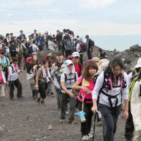 Freeloaders?: A horde of visitors trudges up Mount Fuji last August. The local governments of Yamanashi and Shizuoka may start charging an admission fee to climb Japan\'s highest peak, to raise funds for the preservation of its environment. | KYODO