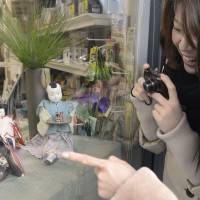 Women check out hina dolls in a storefront display.  | KYODO PHOTO