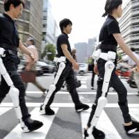 Power assist: Cyberdyne Inc. employees wearing Hybrid Assistive Limb, or HAL, robotic suits are seen in 2009. The gear received safety certification Wednesday by a quality assurance organization. 
 | AFP-JIJI