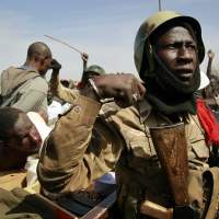 Militant behavior: Malian soldiers guard suspected Islamist extremists in the northern city of Gao on Jan. 29. | AP