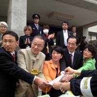 An antinuclear protester hands a petition to a group of Diet lawmakers including former Prime Minister Naoto Kan and Social Democratic Party leader Mizuho Fukushima Sunday in Tokyo. | AYAKO MIE