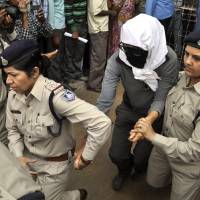 Safety issues: A Swiss woman who police say was gang-raped while touring central India by bicycle with her husband is led to a hospital in Gwalior for a medical examination Saturday. | AP