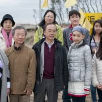 Isao Tsujimoto (front row, second from left) from the Studio for Cultural Exchange and some ASIJ students meet with Mikio Fukuhara (center, front row), Etsuko Asano (back row, left) and Fujiko Suda (back row, second from left), survivors of the Great East Japan Earthquake who contributed tanka poems to the exhibition, on a beach in Natori, Miyagi Prefecture. | SARAH SUTTER