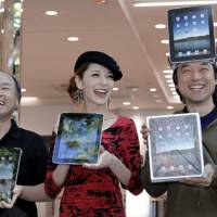 Got a new pad: Kazuaki Miura (right), the first to obtain Apple\'s iPad at a Softbank Corp. store in Tokyo\'s Harajuku district, beams Friday in a congratulatory moment with Softbank Chief Executive Masayoshi Son and model Rina Fujii. | AP PHOTO