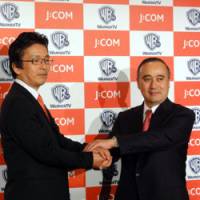 Power players: Hiroyuki Nakatani (left), senior corporate officer of Jupiter Telecommunications Co., and Warner Entertainment Japan Inc. President William Ireton face reporters Wednesday at a Tokyo hotel. | KAZUAKI NAGATA